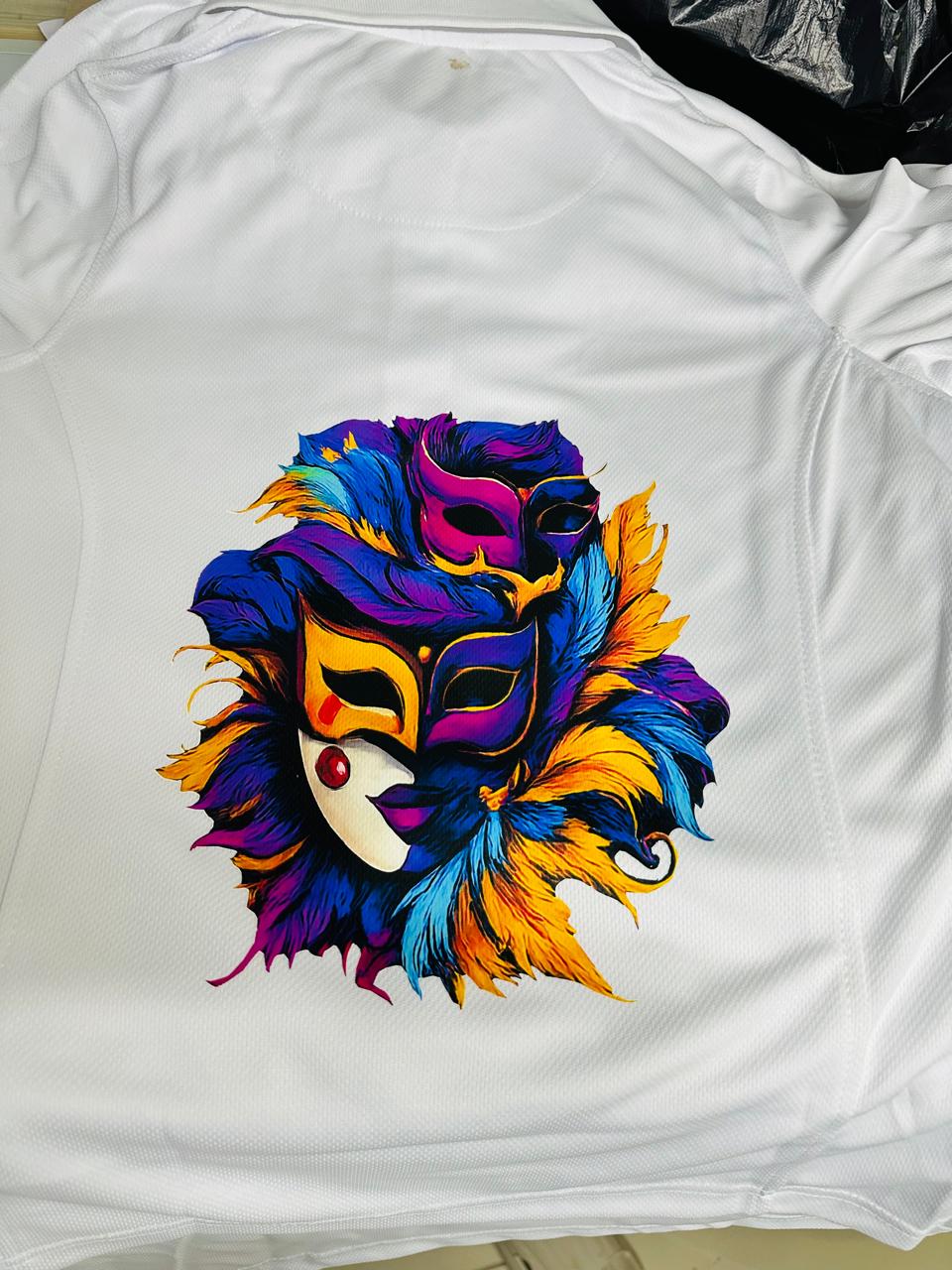 White garment carrying a vivid purple, yellow and cyan carnival mask illustration.